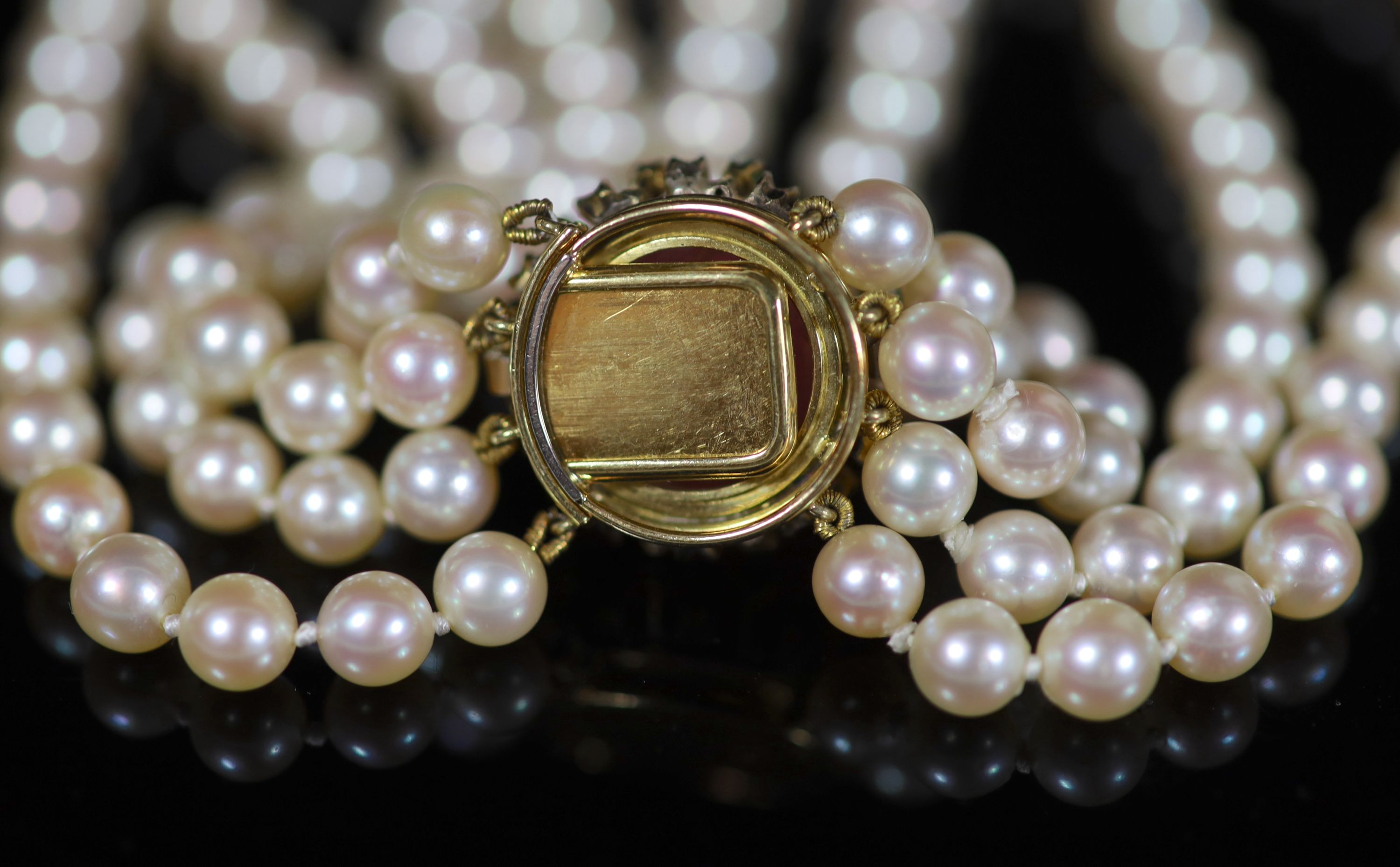 A four-strand graduated cultured pearl choker with circular cabochon pink tourmaline and emerald yellow metal clasp,